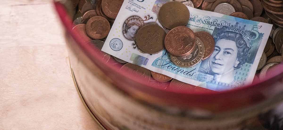 biscuit tin full of small change and a five pound note